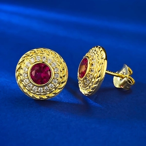 Dettaglio macro di orecchini vintage con rubino rosso e marchio in argento S925 dorato