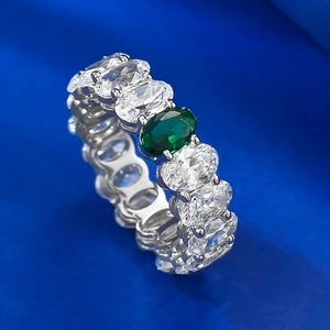Silver ring featuring oval green gemstone and pavé set clear crystals on textured blue base