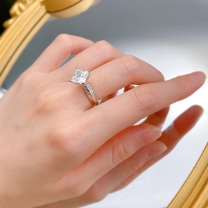 Macro view of a square-cut sparkling gemstone ring with side stones on a silver band