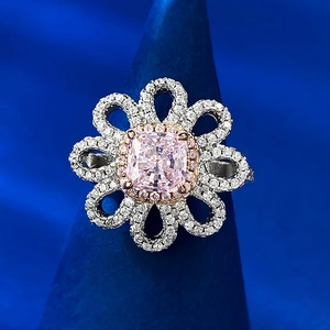 Gros plan d'une bague fleur en or rose avec pierre rose et pétales en halo