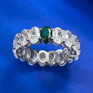 Macro view of oval cut green gemstone ring with side stones on blue texture background