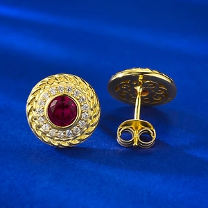 Vista macro di orecchini a perno con rubino e oro con halo di diamanti e bordo a corda