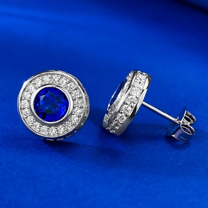 Macro shot of silver stud earrings with round blue zircon and halo setting details