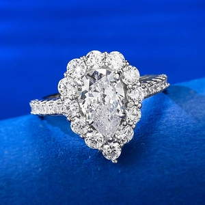 Gros plan sur la bague poire en argent 925 avec halo de diamants sur velours bleu