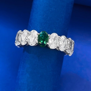 Macro shot of silver ring with oval emerald and white zircon pave setting in detail