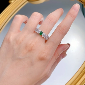 Macro view of emerald-cut green stone ring with rectangular side zircons on hand