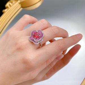 Detailed close-up of a blooming flower ring featuring a red center stone and pavé petals