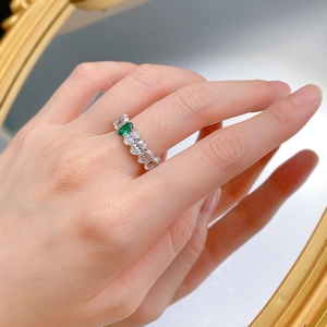 Detail of luxury ring with oval green emerald zircon and shimmering pavé diamonds on hand