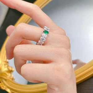 Silver ring featuring emerald green oval zircon and white side stones on hand