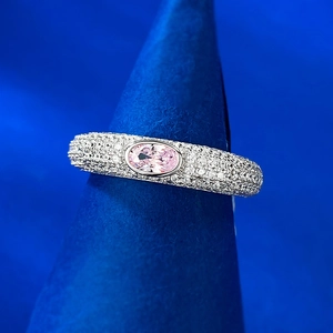 Gros plan d'une bague avec gemme rose ovale et pavage de diamants sur argent