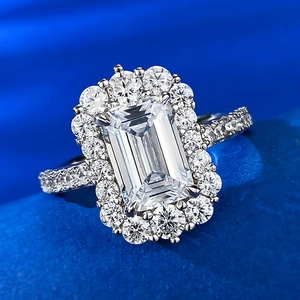 Emerald cut 925 sterling silver halo ring with pavé side stones on deep blue velvet