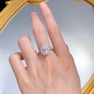 Gros plan d'une bague en argent en forme de poire avec halo de diamants sur la main