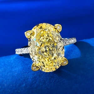 Oval yellow carbon diamond ring with heart-shaped golden prongs on a blue velvet background