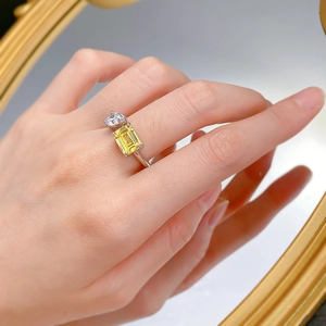 Detailed view of an open silver ring featuring emerald cut yellow stone and round crystal