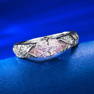 Macro shot of marquise-cut pink diamond ring with sparkling side stones on blue surface