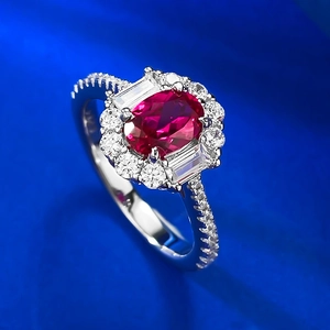 Macro side view of an oval sapphire-style ring with sparkling diamond halo on blue silk