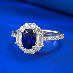 Macro shot of oval sapphire ring with halo diamonds on a luxurious silk fabric