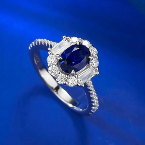 Macro detail of oval blue sapphire ring with cluster diamonds on silk background