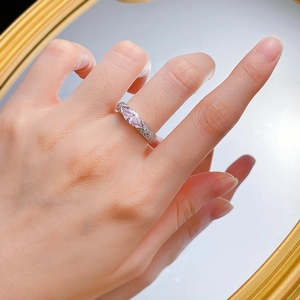 Close-up of marquise-cut pink gemstone ring with pavé side stones on a silver band