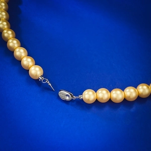 Glänzende goldene Südsee-Perlenkette mit S925 Sterlingsilber-Verschluss auf Blau