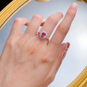 Detail of oval-cut sapphire ring on hand featuring a halo of diamonds and silver band