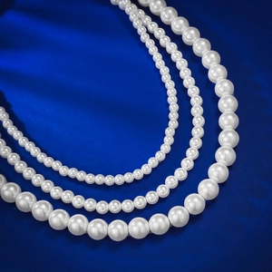 Lustrous 8mm round white pearl necklace in three sizes on a navy blue background