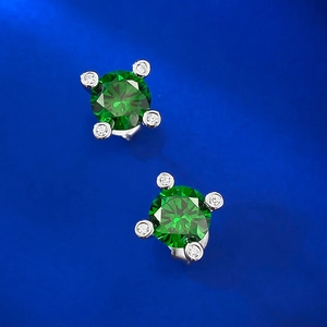 Close-up of 1ct green sapphire stud earrings with four-prong silver setting and accents