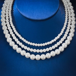 Close-up of three-layered round white pearl necklaces displayed on dark blue bust stand