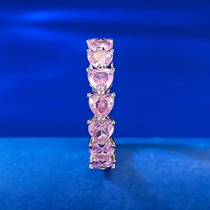 Macro detail of six pink heart-shaped gemstones in silver prong settings for rings