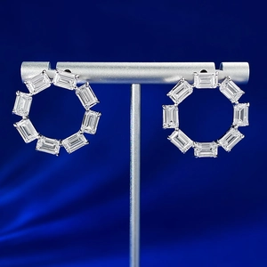 Macro shot of silver square-cut emerald stones on earrings with jewelry display stand