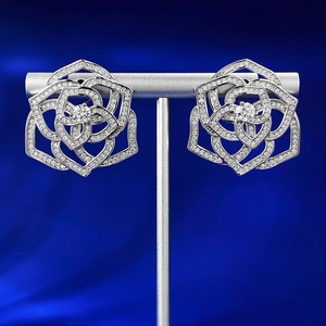 Macro shot of 925 silver hollow rose earrings with pavé zircons on blue velvet background