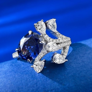 Macro shot of oval blue gemstone ring with pear-cut side stones on blue silk background