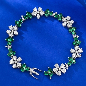 Detail of S925 silver flower bracelet with green leaves on blue textured fabric