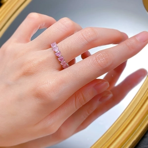Detail of pink heart-shaped crystal pavé ring worn on finger in a refined setting