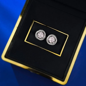 Vue macro des boucles d'oreilles halo en pierre rose dans un écrin de luxe