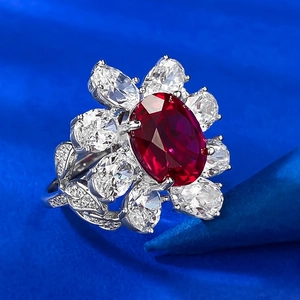 Macro shot of oval red gemstone ring with petal-shaped diamond halo and leaf engraving
