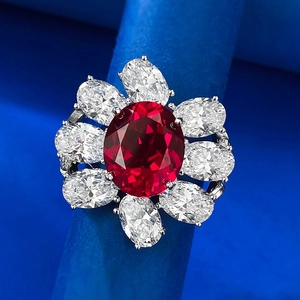 Macro shot of oval red ruby cluster ring with white gemstone halo in silver setting
