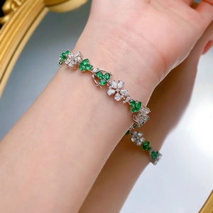 Detailed view of S925 silver floral bracelet featuring green stones on a model wrist
