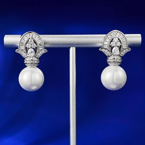 Macro detail of 925 silver pearl drop earrings with sparkling cubic zirconia on blue velvet