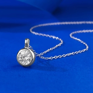 Gros plan d'un pendentif en argent S925 avec serti clos et pierre ronde sur chaîne fine