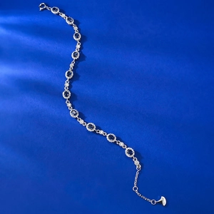 Detailed view of S925 sterling silver stamp and blue oval sapphire charm on the bracelet