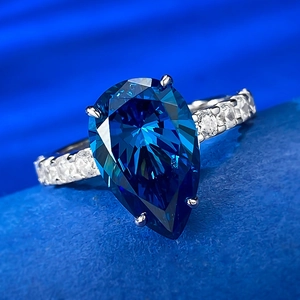 Macro di un anello con zaffiro blu a pera con pietre bianche scintillanti e fascia argento