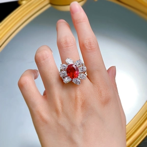 Macro detail of oval red gemstone ring with marquise cluster setting on hand