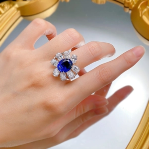 Luxurious oval blue sapphire ring with flower zircon halo shown on a model's finger