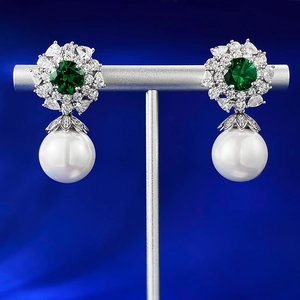Detail of 925 silver cluster earrings featuring green gemstones and large white pearls