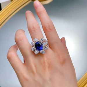 Detailed close-up of a blue sapphire oval ring with pear-cut halo on a silver band