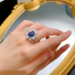 Macro detail of oval blue sapphire ring with a floral halo on silver metal band