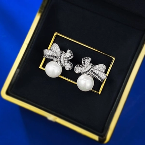 Macro view of bowknot pearl earrings with zircons in a premium velvet jewelry box