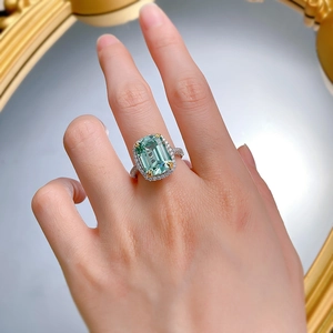 Detailed macro view of an emerald-cut green tourmaline ring with sparkling diamond halo