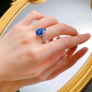 Dettaglio dell'anello con zaffiro blu reale a goccia e pavé di diamanti sulla mano